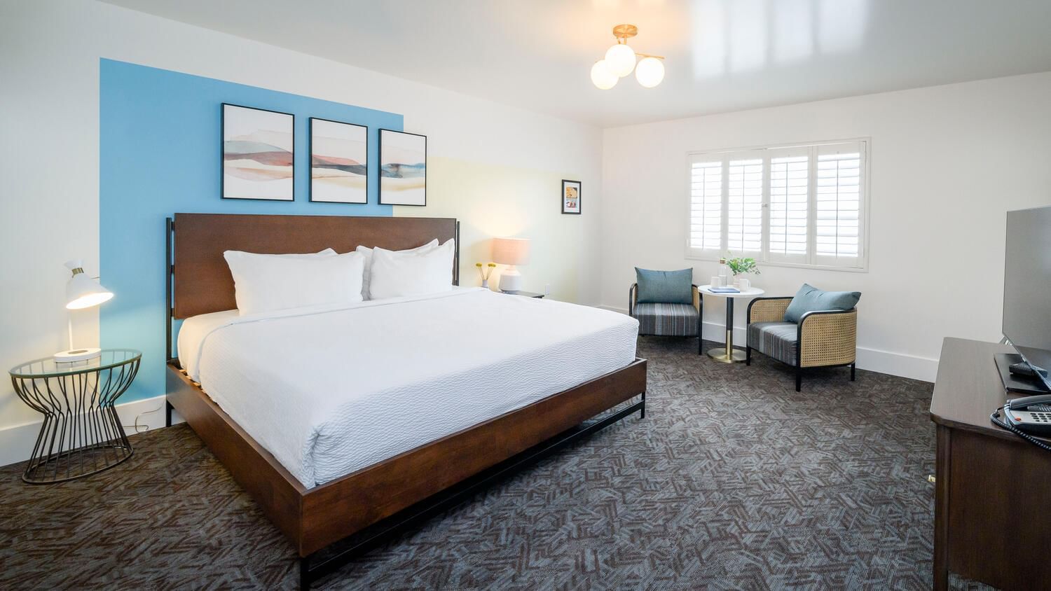 A hotel room with a large bed, two chairs, and a window.