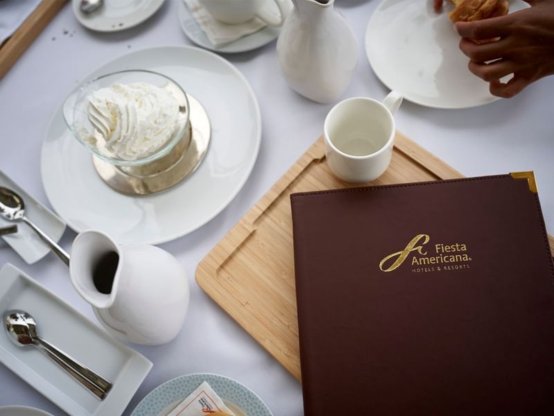 Breakfast table with dessert, utensils and a menu at Grand Fiesta Americana