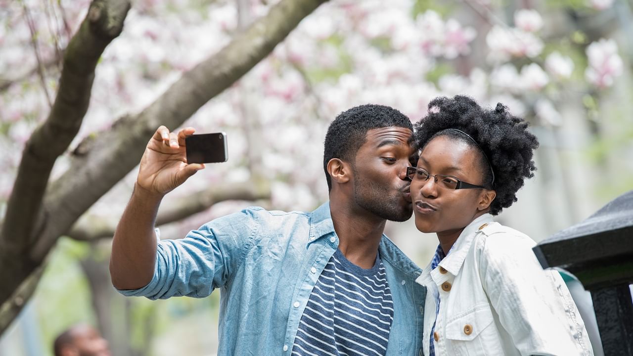 man kissing a woman under cherry blossoms