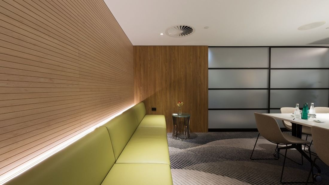 Elegant Elara Boardroom interior with wooden walls, green bench, and modern furniture at Pullman Sydney Olympic Park.