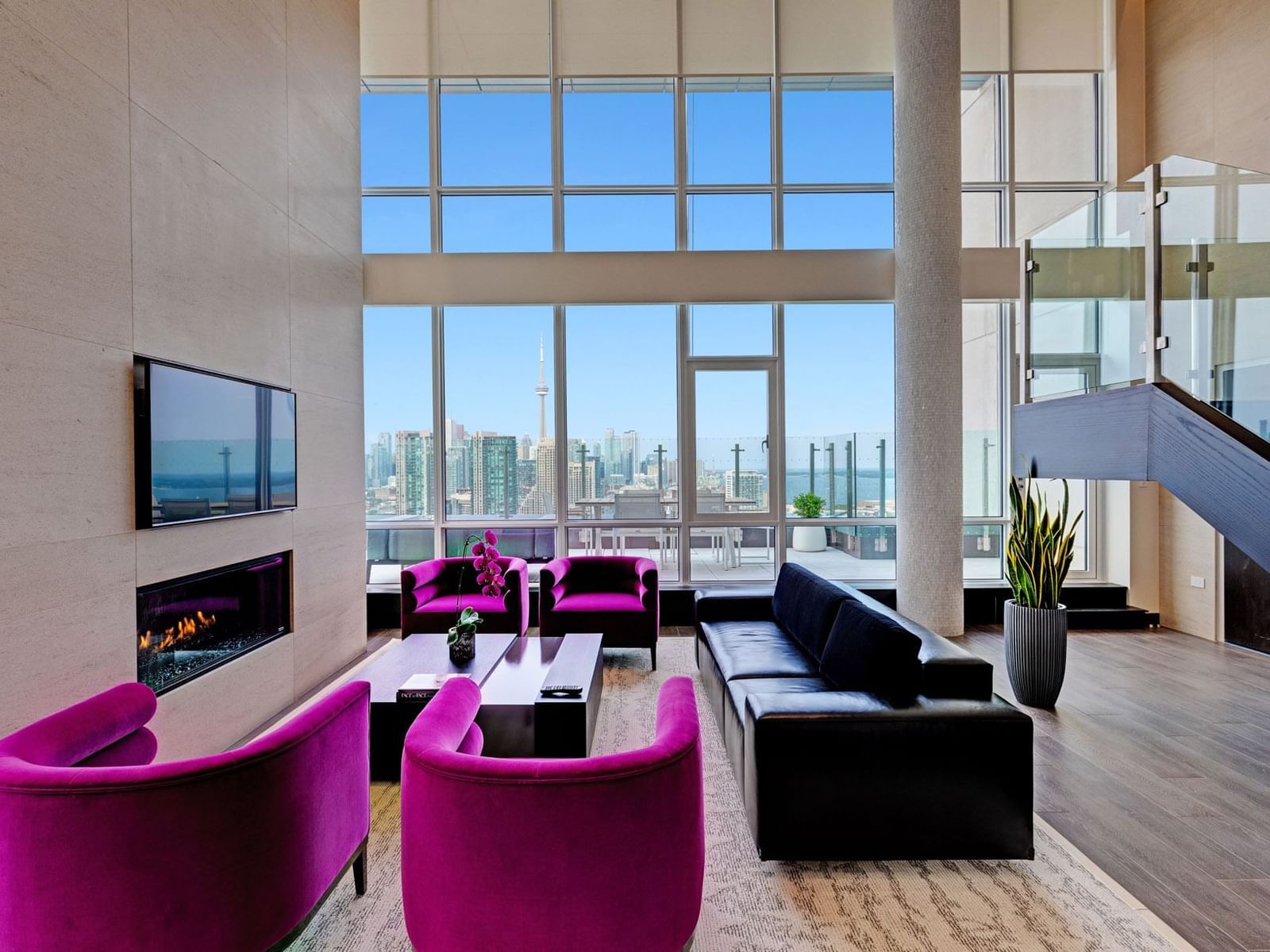 Living area with plush seatings, large windows, fireplace, and a city view in Bi-Level Penthouse Suite at Hotel X Toronto