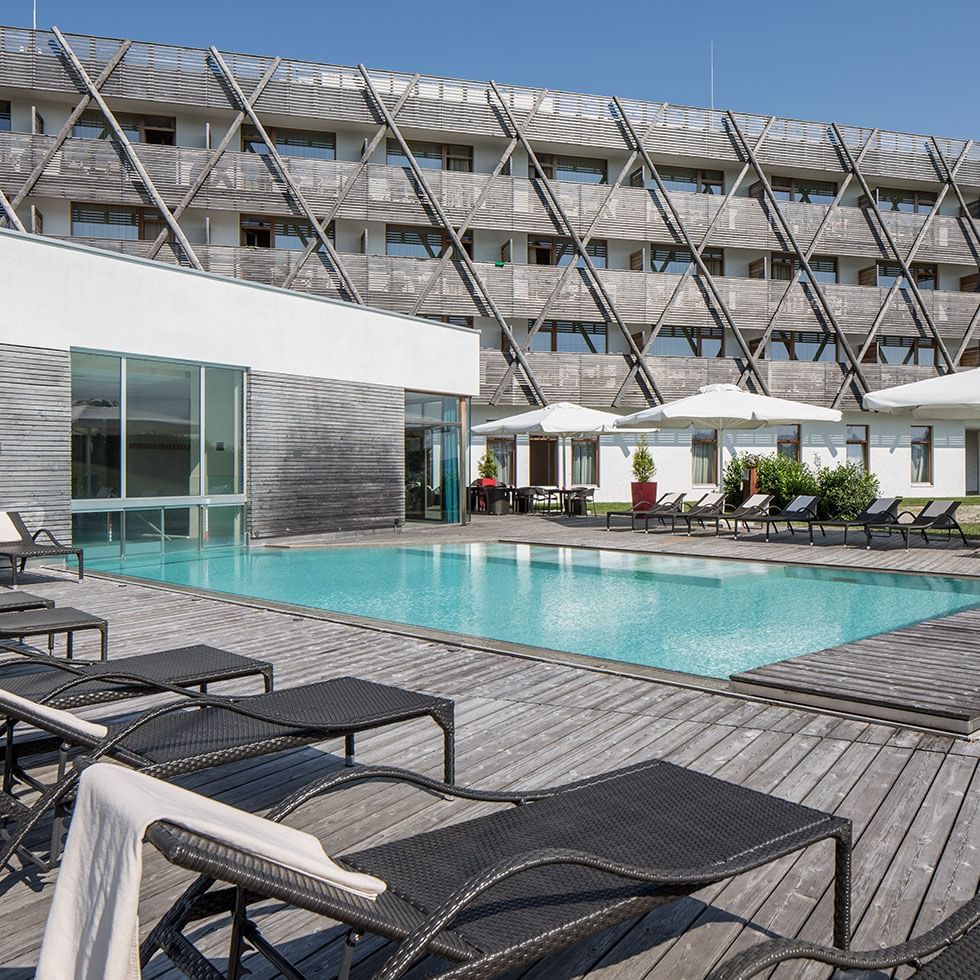 Outdoor pool area with sunbeds at Falkensteiner Hotels