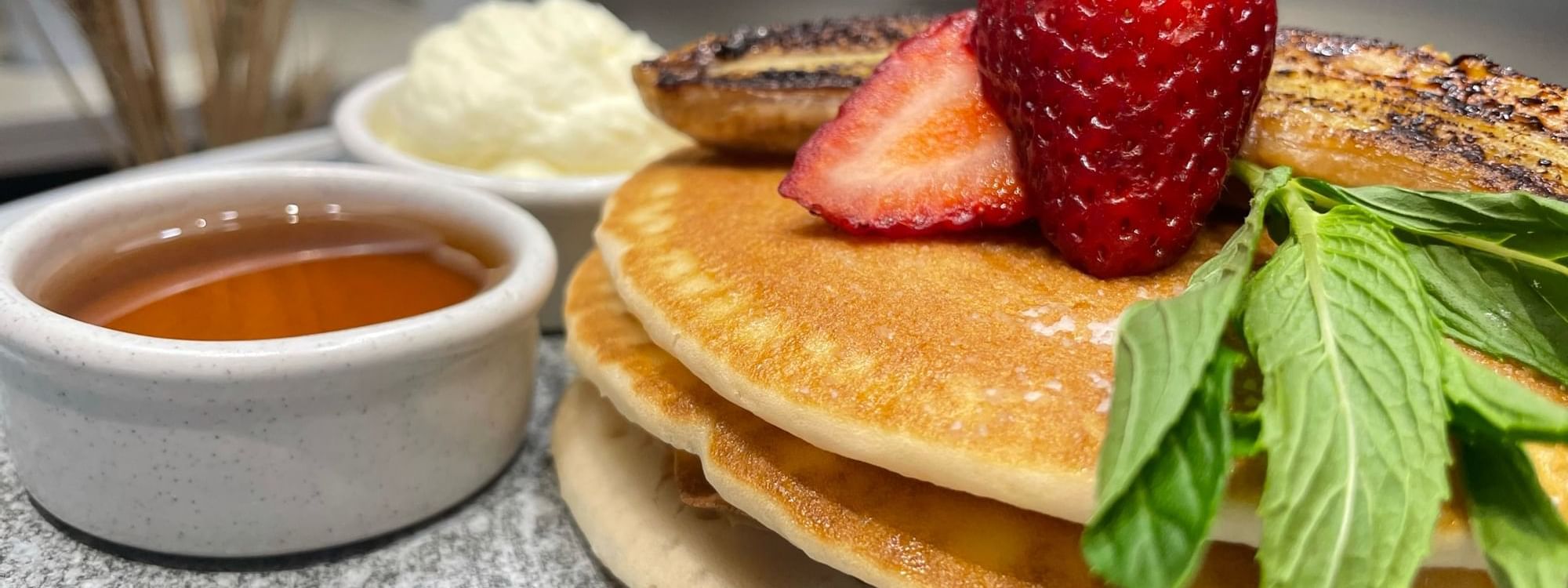 Fluffy pancakes topped with banana and strawberries served at Novotel Sydney International Airport
