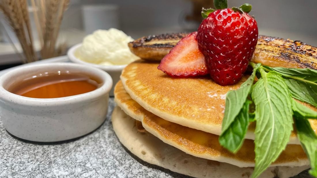 Fluffy pancakes topped with banana and strawberries served at Novotel Sydney International Airport