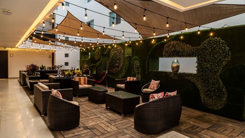Illuminated lounge area with string lights, sofas, coffee tables & wooden floor at Gamma Puebla Senorial Centro