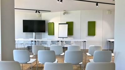 Classroom-style arrangement facing a TV & flip chart in a T2 at the Avaneo Hotel Marktredwitz, a hotel with conference rooms