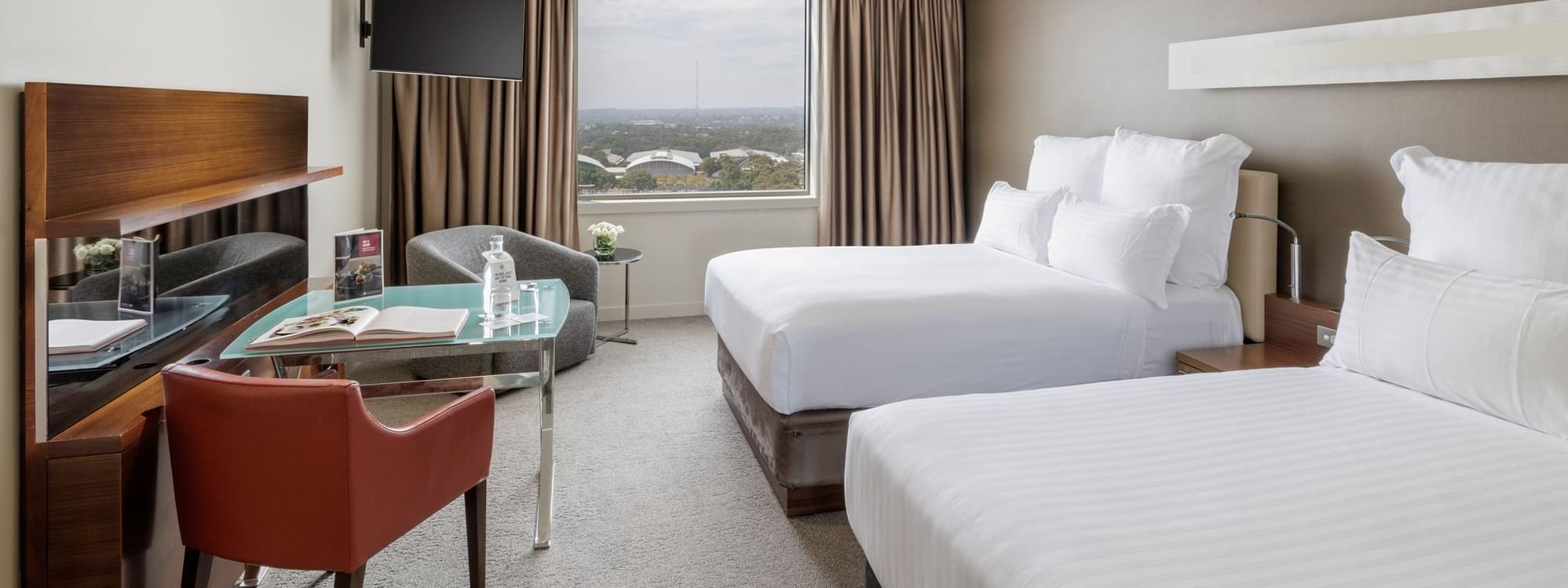 TV with work desk facing two beds by the window in the Pullman Superior Double room at Pullman Sydney Olympic Park
