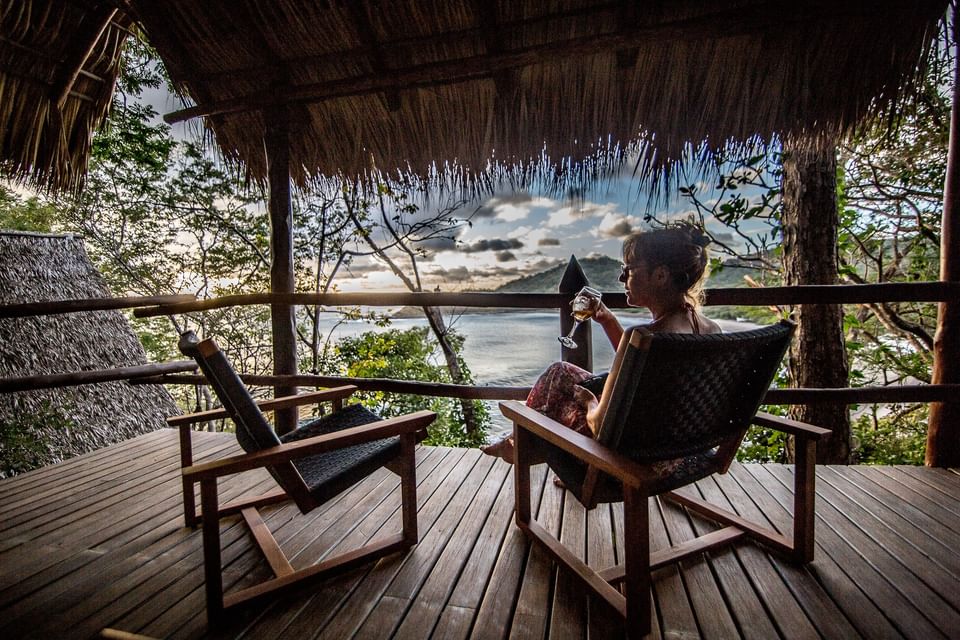 Guest enjoying a glass of wine on a private deck overlooking the sunset at Morgan\'s Rock, one of the San Juan del Sur hotels