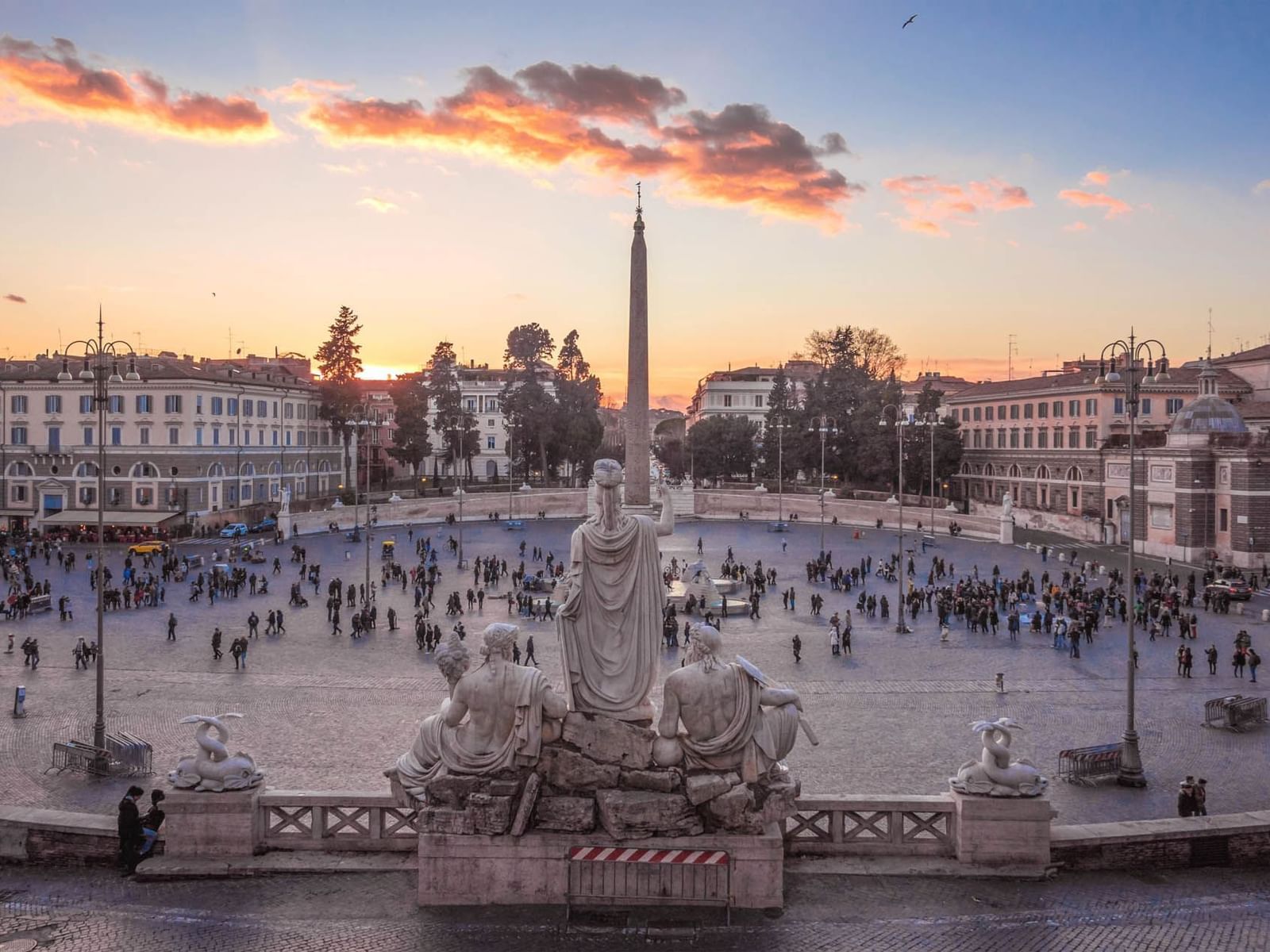 Sunset view over Piazza del Popolo with people, historic buildings, and statues, near The Guardian Hotel