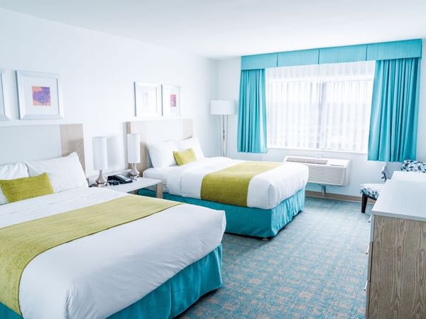 Two beds in hotel room with blue and green colors