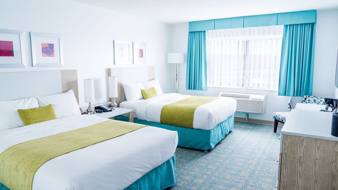 Two beds in hotel room with blue and green colors