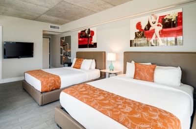 Spacious Superior Double Queen Balcony with two beds, TV, and vibrant orange accents in a modern Riviera Hotel South Beach