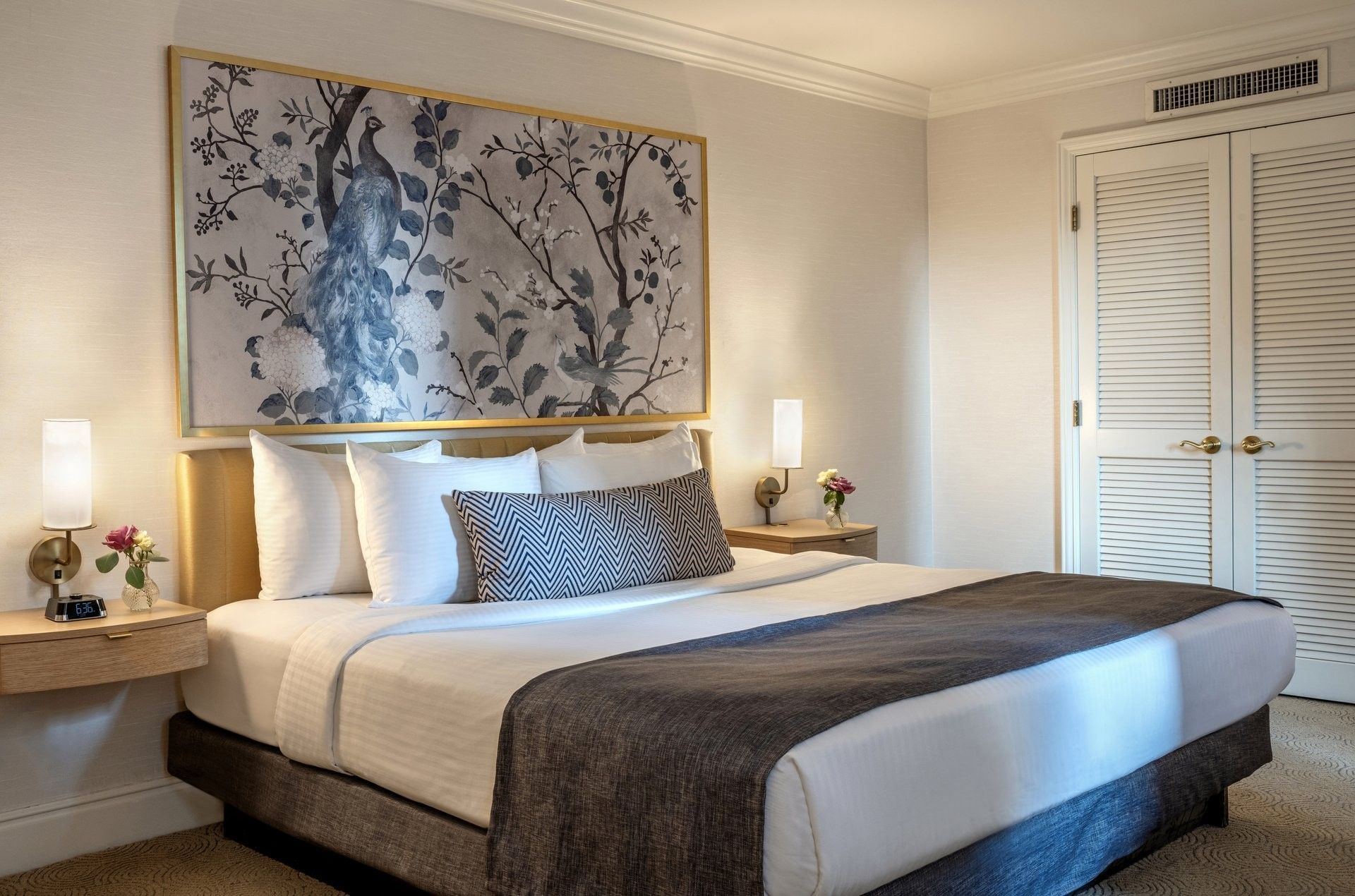 Elegant hotel bedroom with large bed, decorative wall art, and side lamps at Warwick Allerton Chicago.