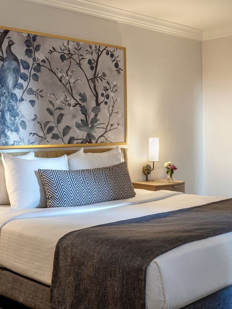 Bed between the side tables under pattern wall art in the King Room at Warwick Allerton Chicago
