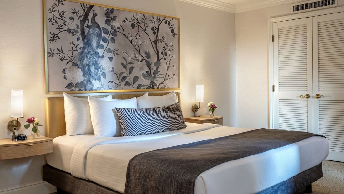 Bed between the side tables under pattern wall art in the King Room at Warwick Allerton Chicago