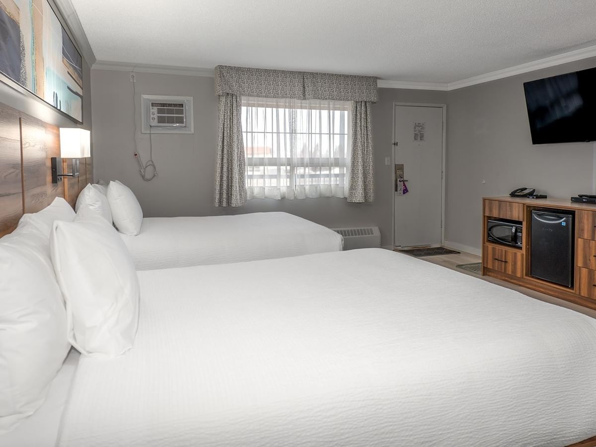 Two queen beds, television, and amenities in a room at Coast Dawson Creek Hotel.