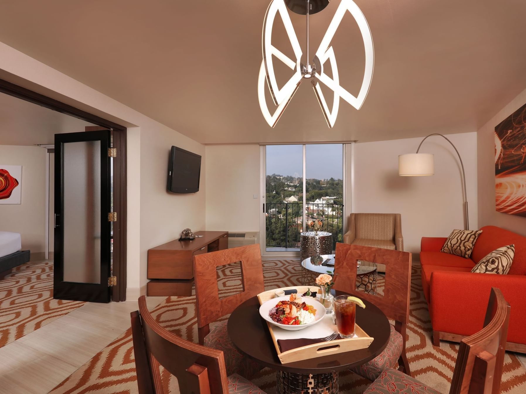 A wide view of a hotel suite with a dining area, living area, and balcony.