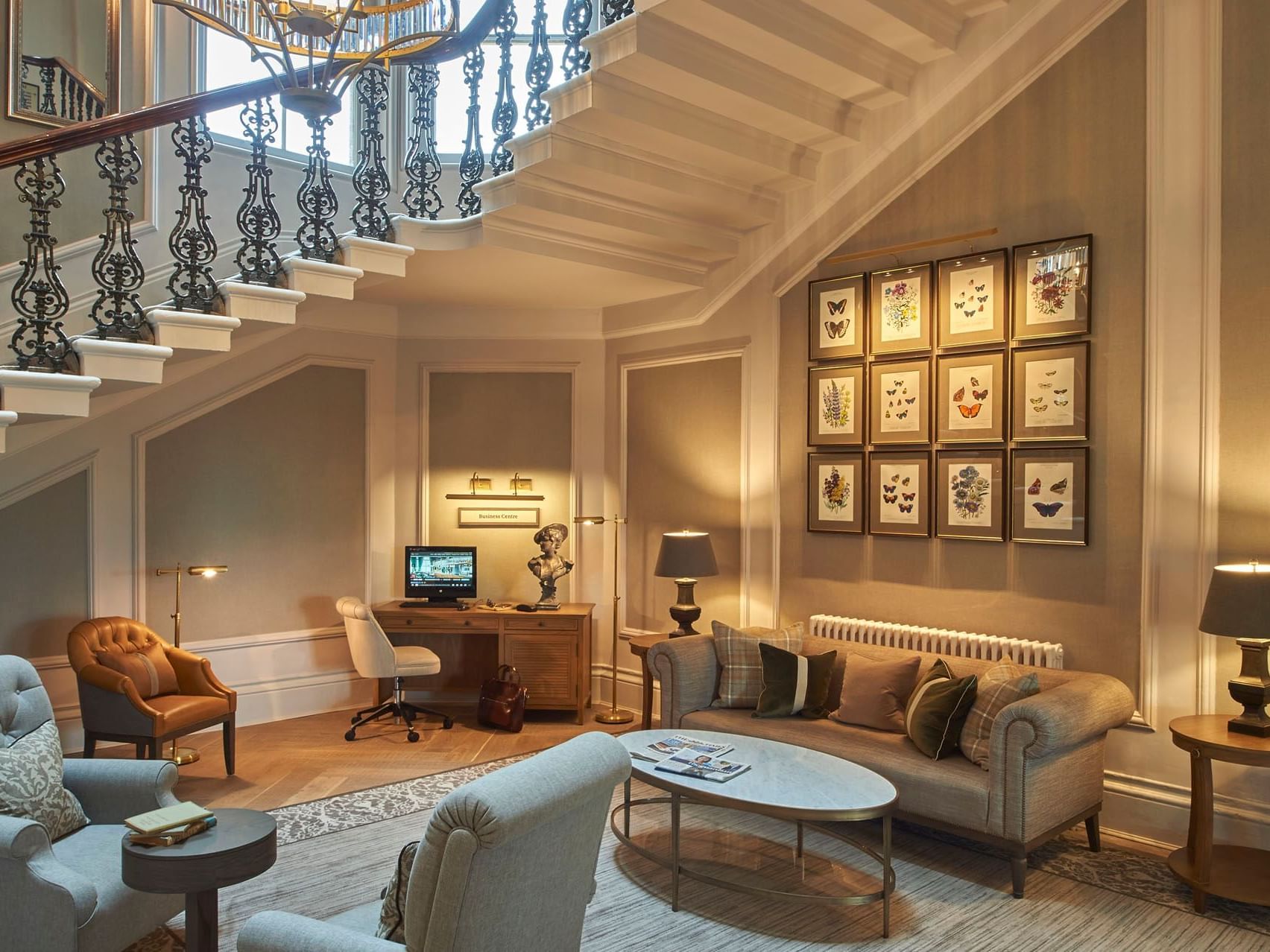 Living room with a spiral staircase, framed butterfly art, and cozy furniture at The Milner York