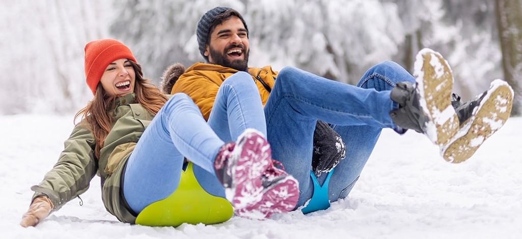 couple sliding down a snowy hill