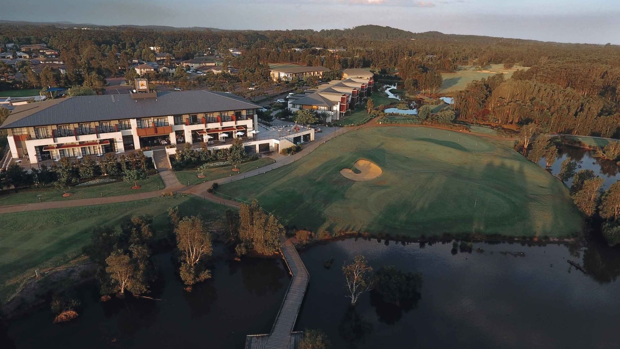 Aerial view of Mercure Kooindah Waters beside a golf course with green fairways and a pond