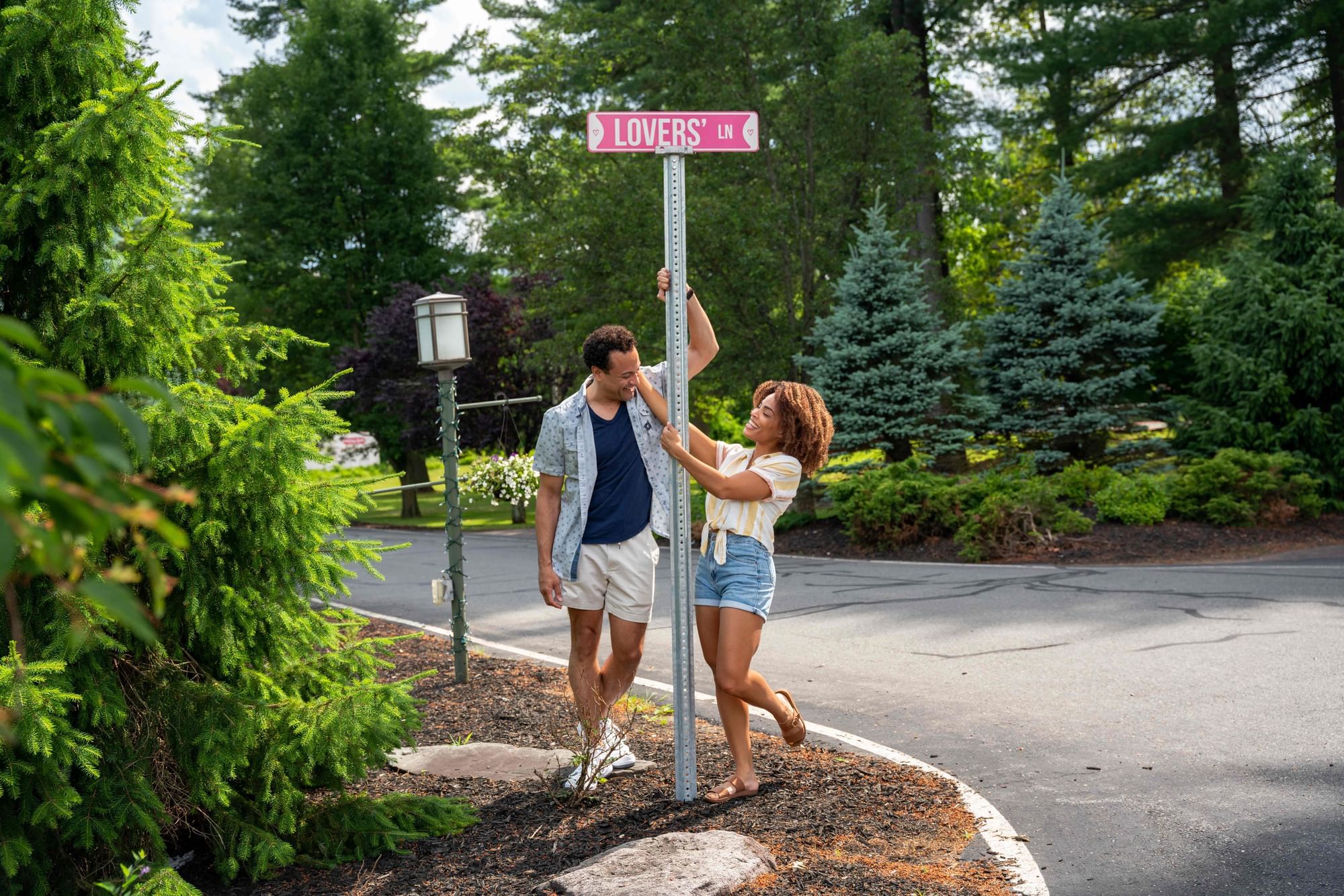 A couple stands together beside a street sign, smiling and enjoying their time outdoors at Cove Pocono Resorts