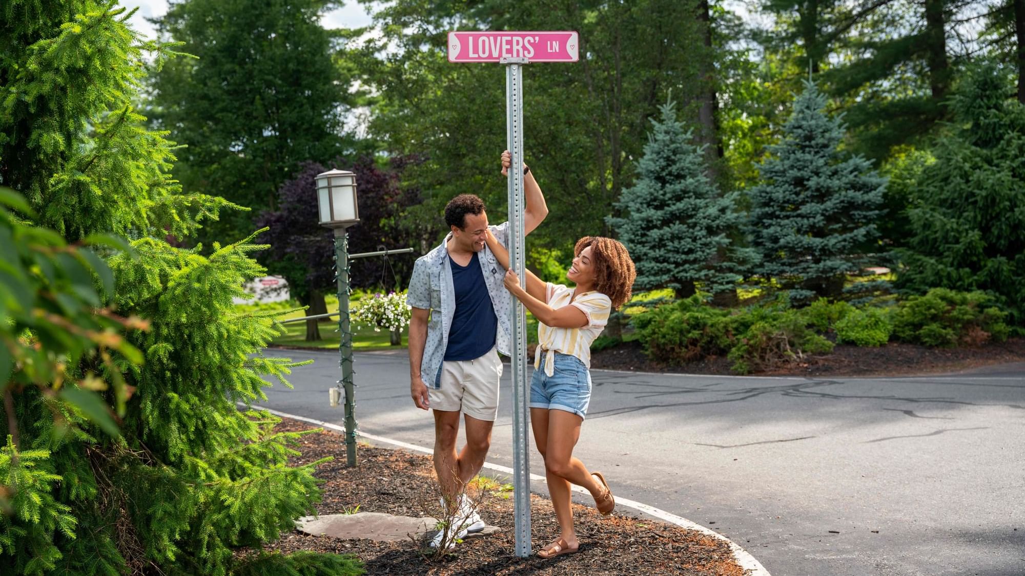 Couple hanging around the Lovers street sign near Cove Pocono Resorts