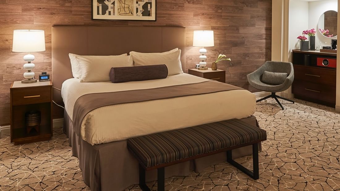 Cozy bed with side tables and dressing table in Executive Junior Suite at Warwick Denver