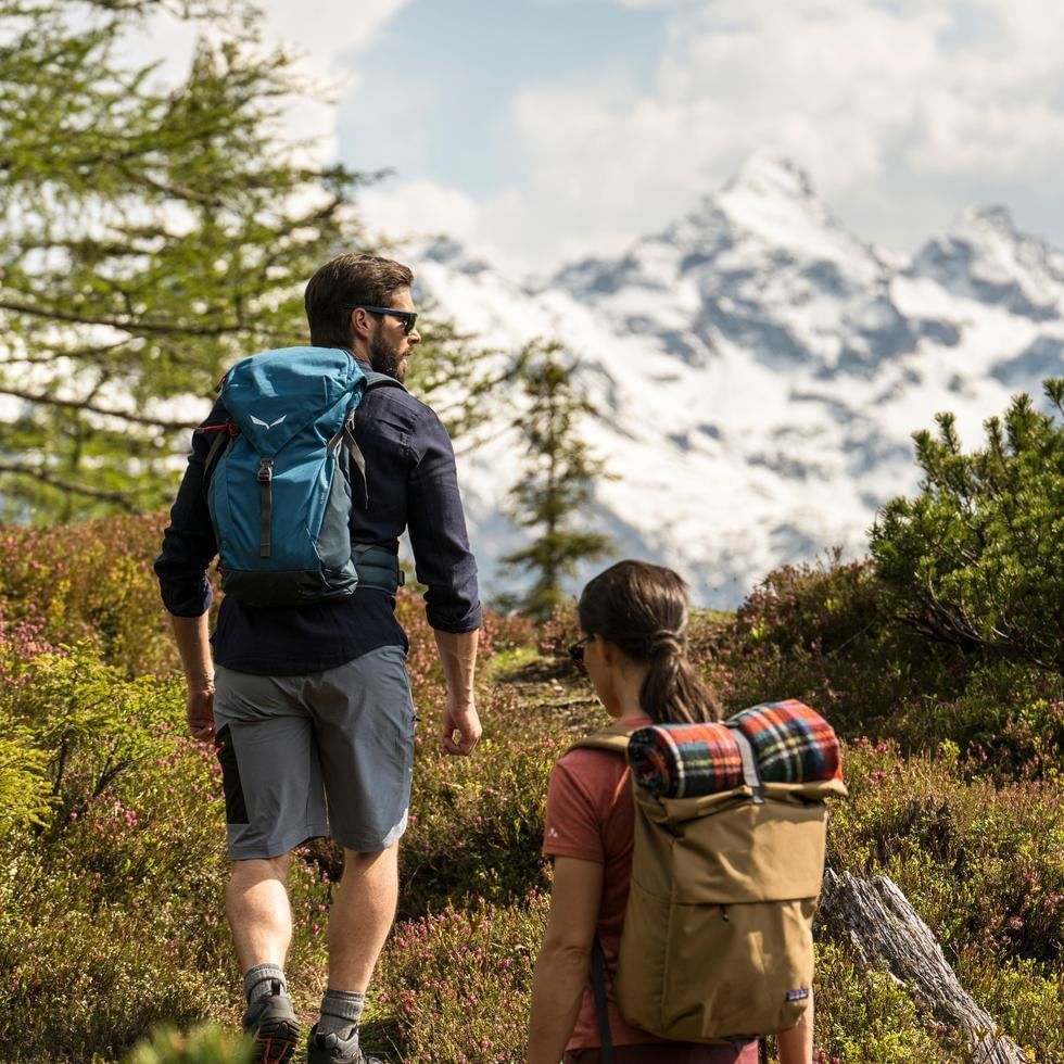 Couple hiking with backpacks and mountain view in the background.