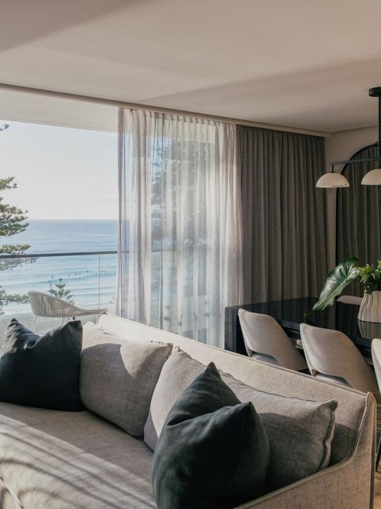 Coastal Two Bedroom Suite at Elysium Manly with a grey sofa by sheer curtains under a pendant light near an arched mirror