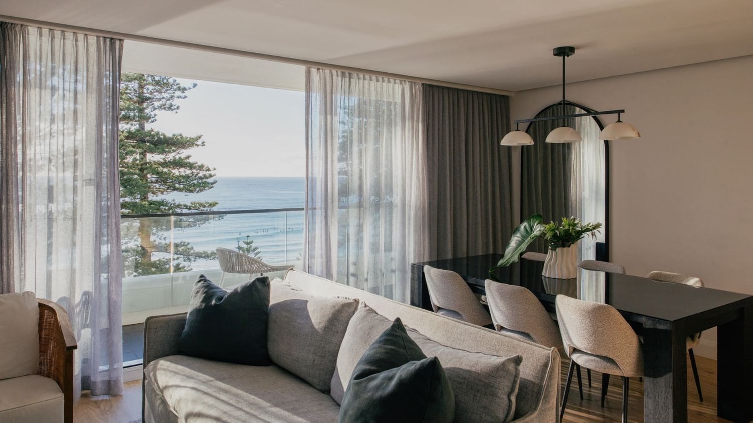 Coastal Two Bedroom Suite at Elysium Manly with a grey sofa by sheer curtains under a pendant light near an arched mirror