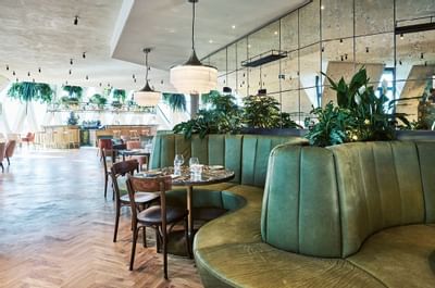 Dining area with green velvet seating and elegant lighting in Chez Bernard Restaurant at Hotel Motto Vienna