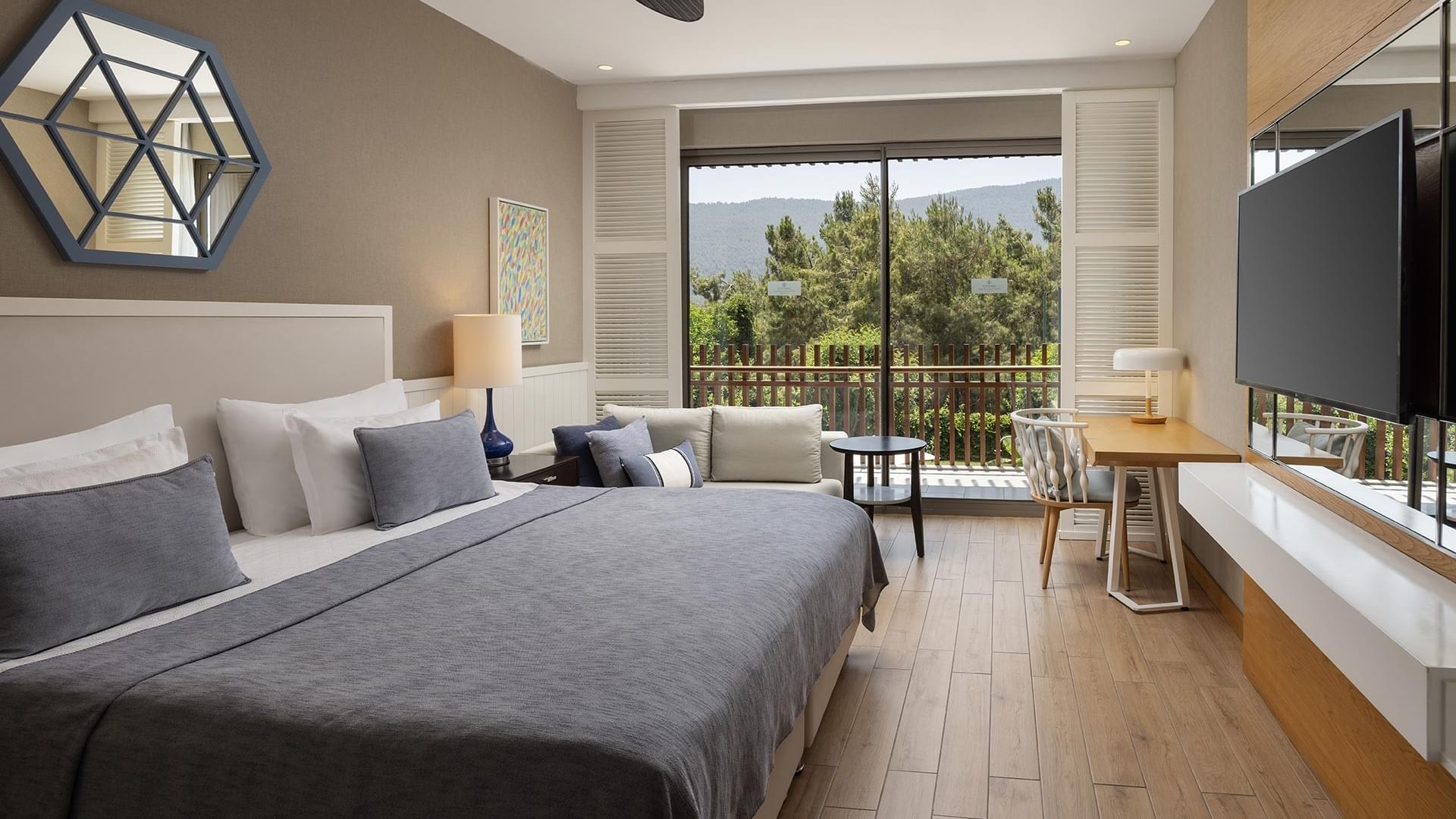 Titanic Luxury Bodrum’da şık dekorlu, yeşillik manzaralı, çalışma masalı ve çift kişilik yataklı Exclusive Villa yatak odası.