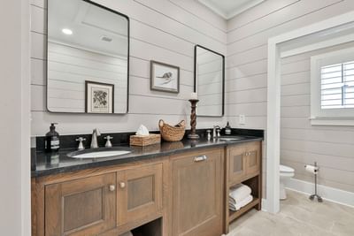 Modern cottage bathroom with dual sinks, cabinets, and stylish mirrors by Cottages at Laurel Brooke