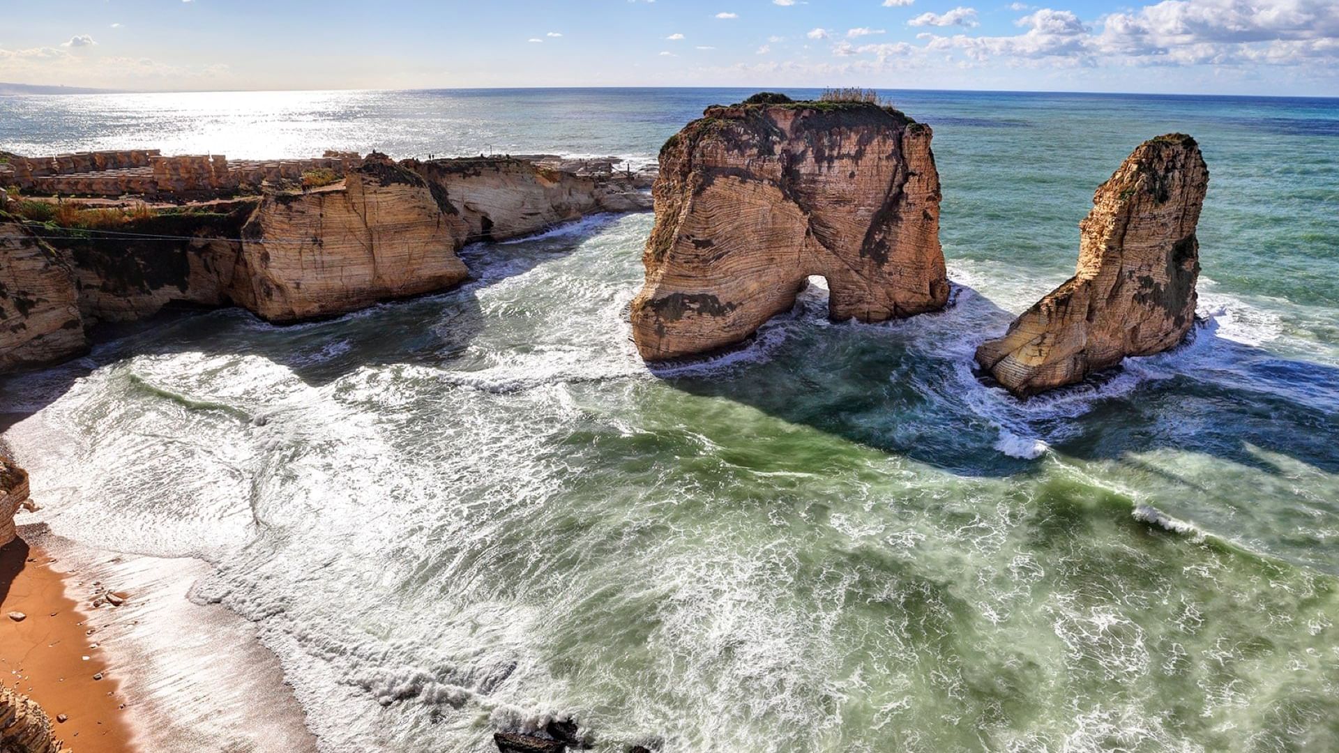 Aerial view of two large rock formations rising from coastal waters featuring Beirut beach near Warwick Hotels and Resorts
