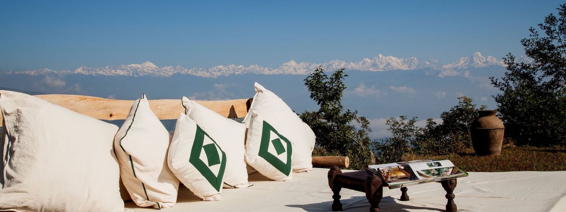 Outdoor lounge area with plush cushions overlooking majestic snow-capped mountains near Dwarika’s Hotels and Resorts