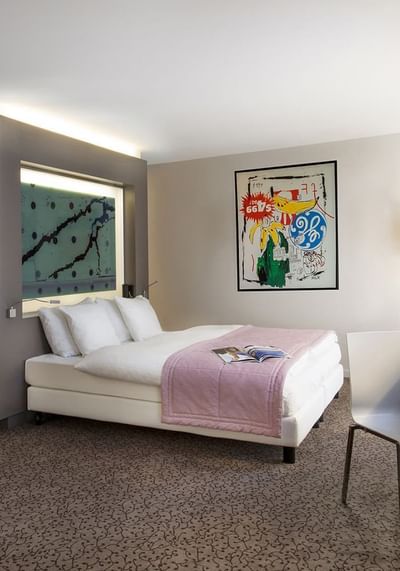 Work desk, TV & an art hung by the bed in Junior Suite at Starling Hotel Lausanne accommodation