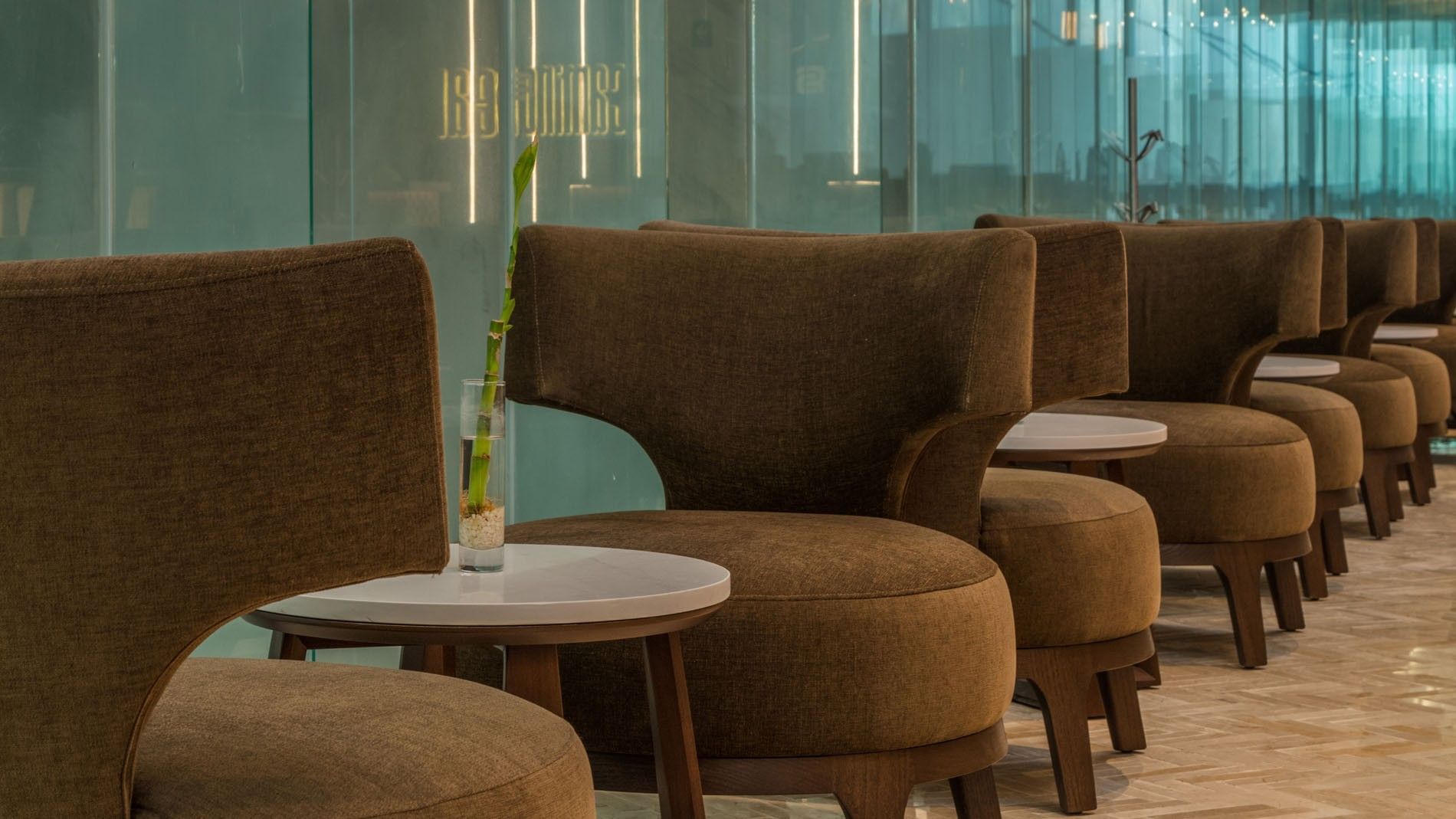 Comfortable brown velvet lounge seating in Lobby Bar with small marble tables and glass accents at Camino Real Merida