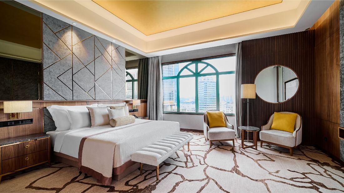 Bed with ottoman and seating by the window in Premier Suite at Sunway Resort