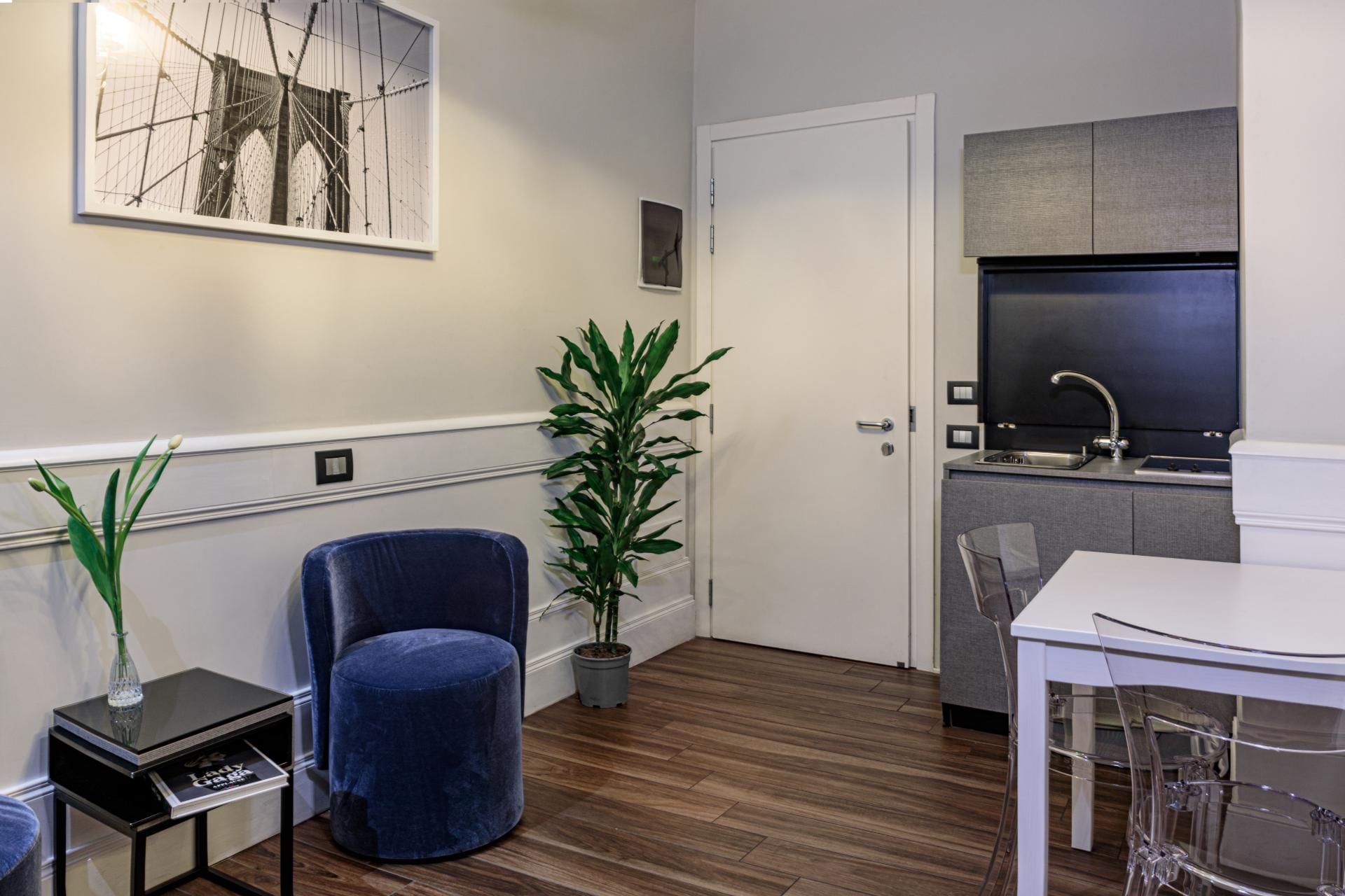 Modern Family Room at The Independent Suites with a blue velvet chair, dining table, and kitchenette