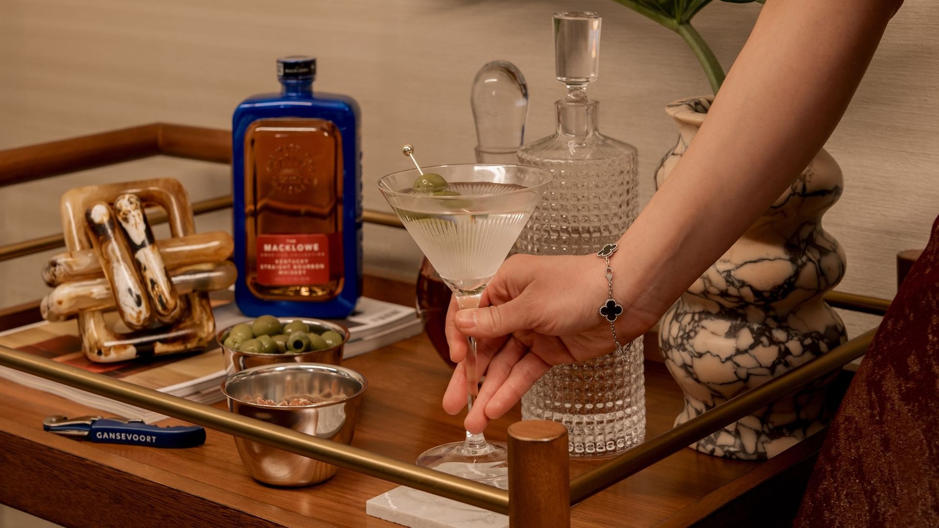 Guest preparing a cocktail at a stylish bar cart in the Two-Bedroom Gansevoort Suite at Gansevoort Meatpacking NYC.