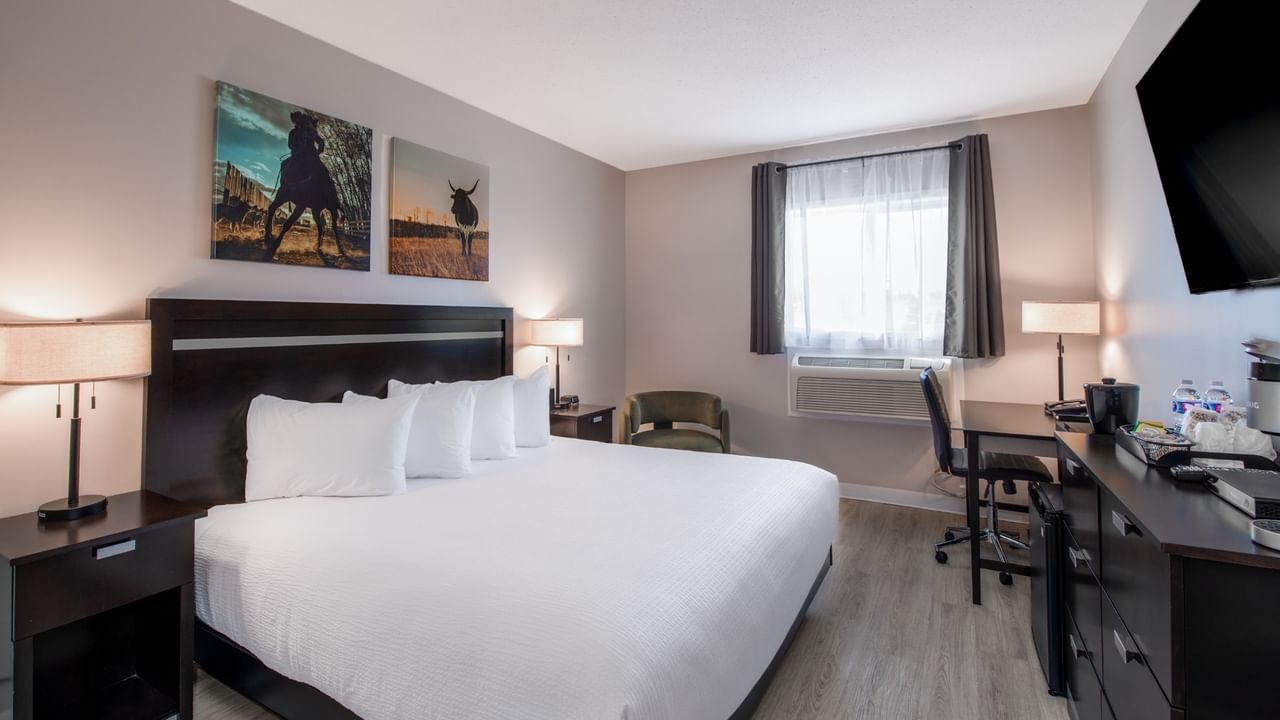King bed at Coast Innisfail Hotel with bedside lamps and seating area