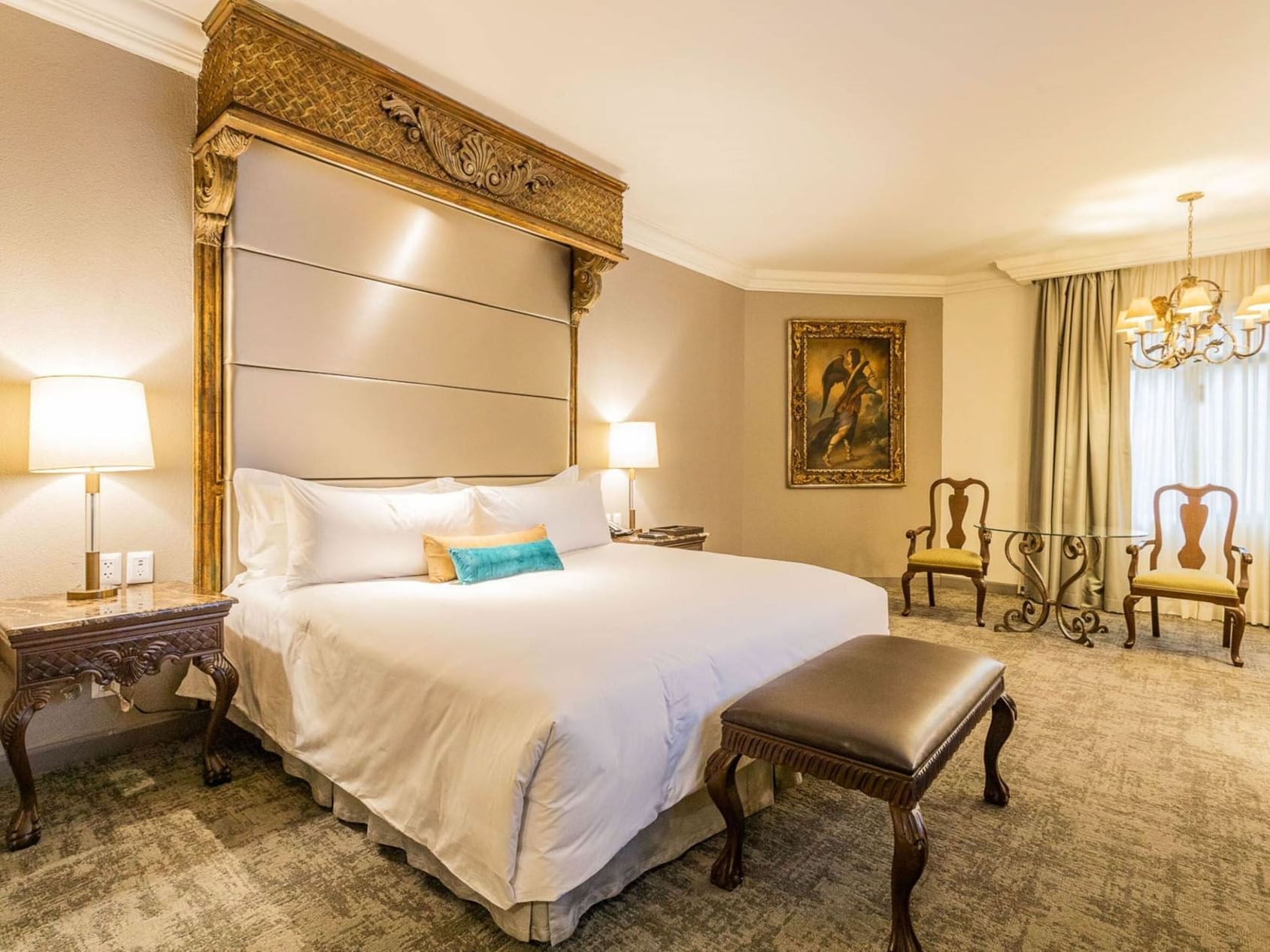 King Master Suite at Quinta Real Monterrey with a leather bench, ornate side table, and classic oil painting on wall