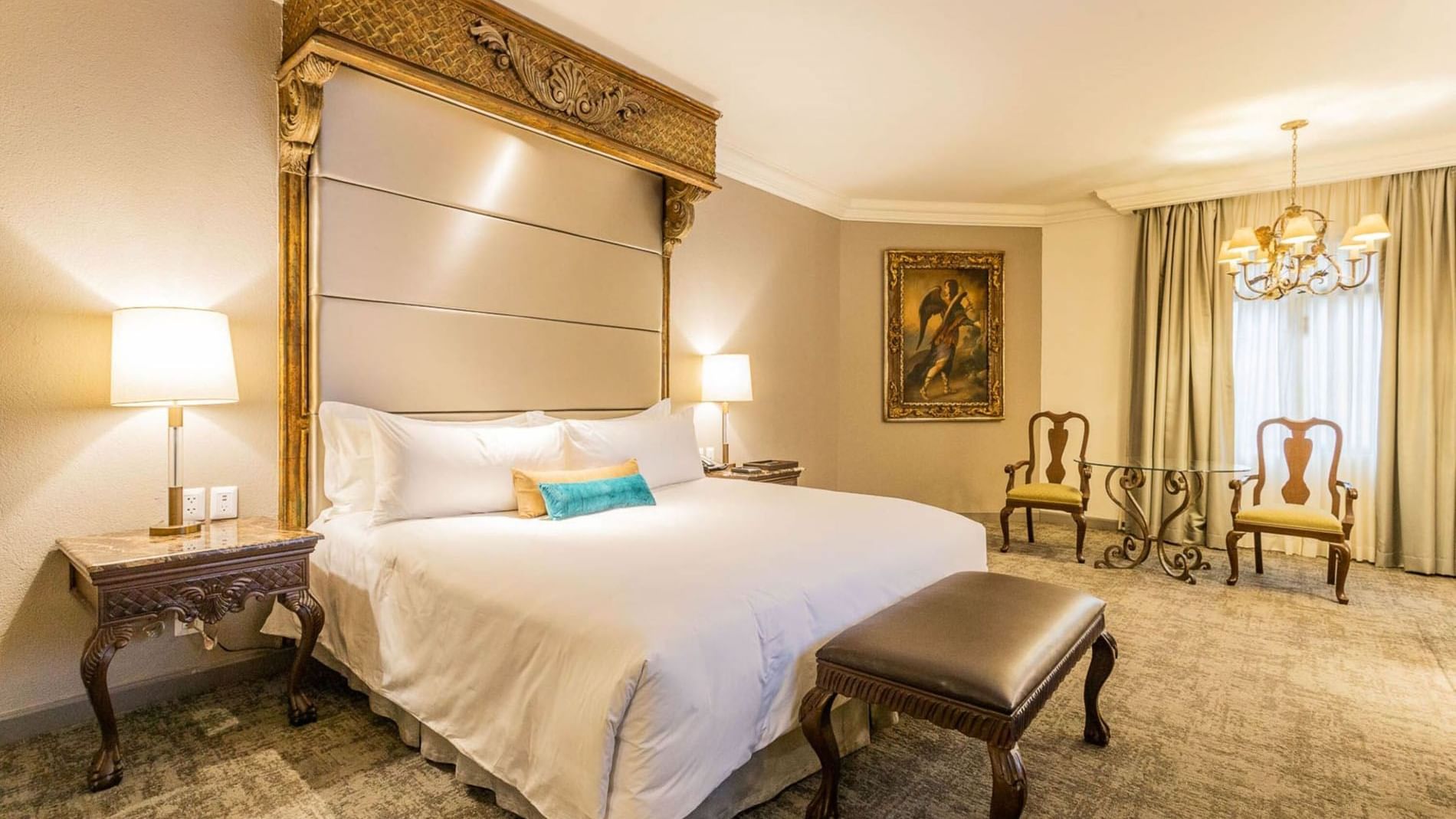 King Master Suite at Quinta Real Monterrey with a leather bench, ornate side table, and classic oil painting on wall