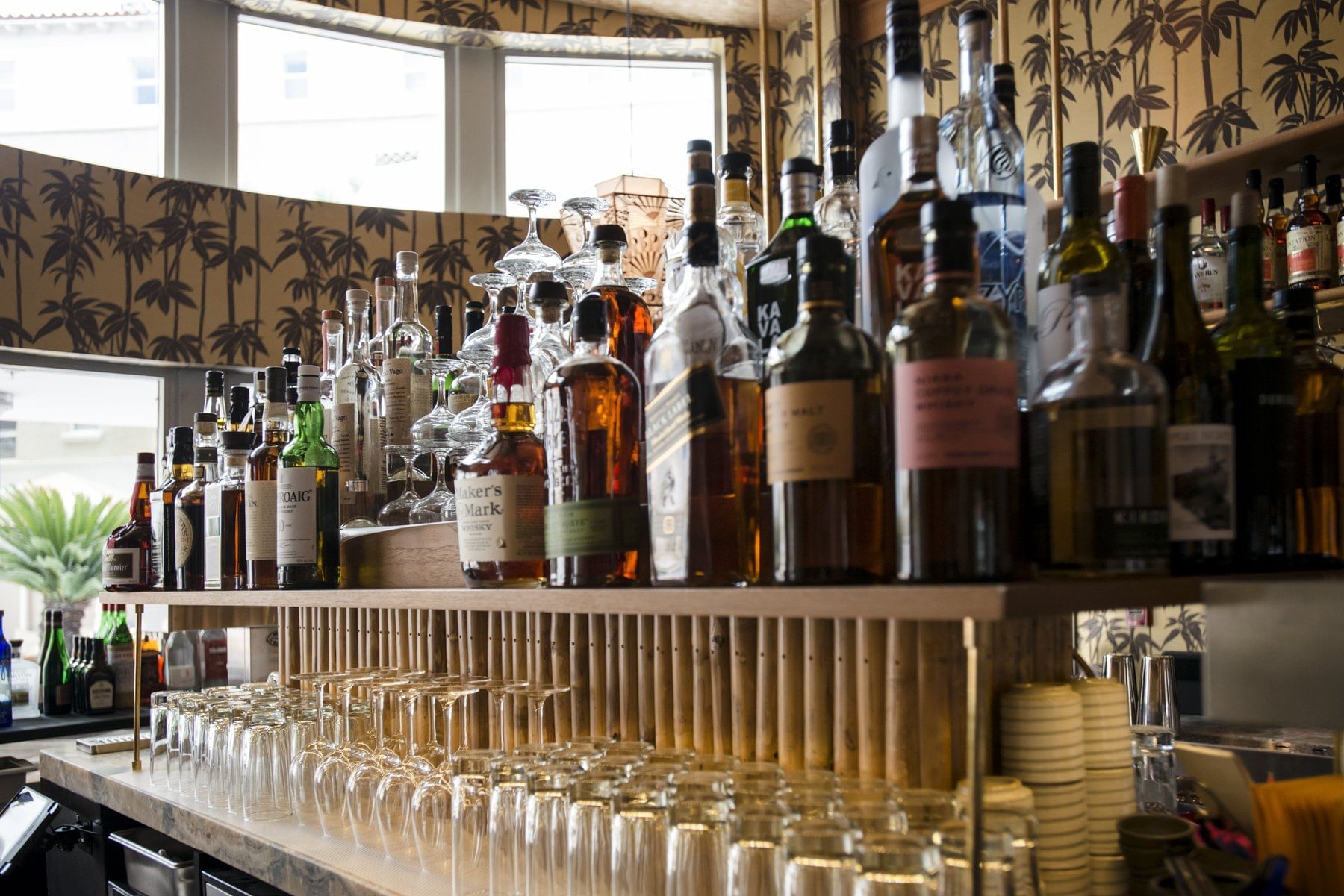 A well-stocked bar with numerous bottles and glasses on a marble countertop