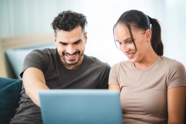 Couple exploring potential wedding venues on their laptop