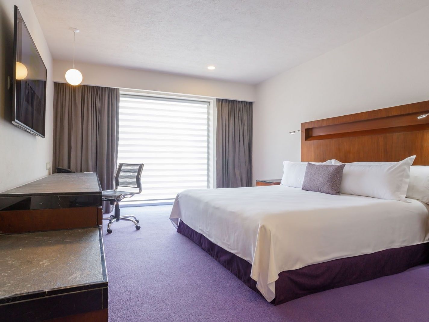 King Deluxe room featuring a king bed, work desk, and purple carpet  at Camino Real Pedregal Mexico