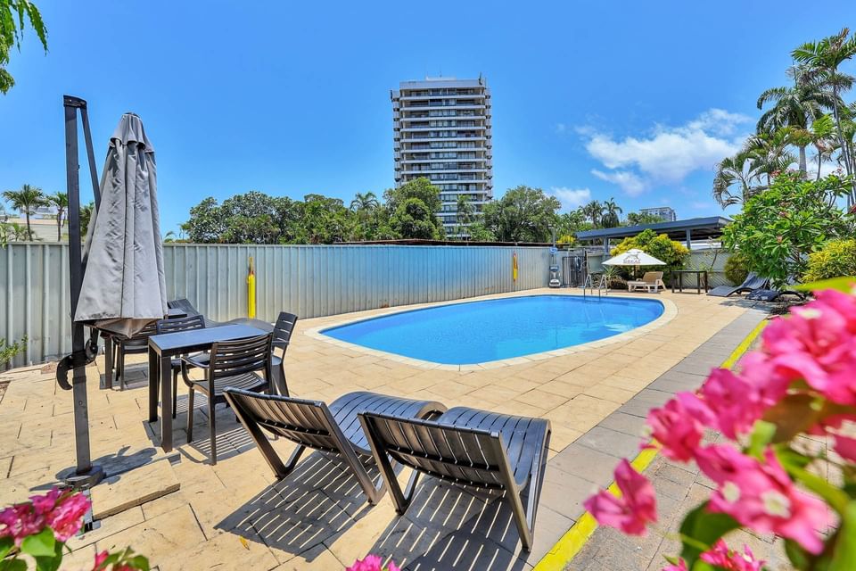 Outdoor pool area with loungers and a table set at Darwin Poinciana Inn in Mitchell St