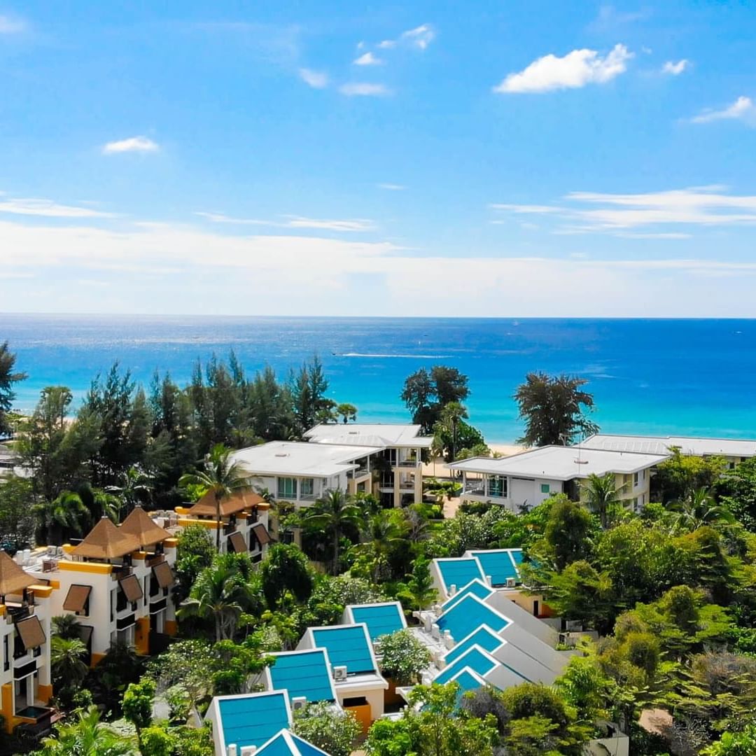 A stunning view of the crystal-clear turquoise waters of Karon Beach, surrounded by a lush tropical garden.