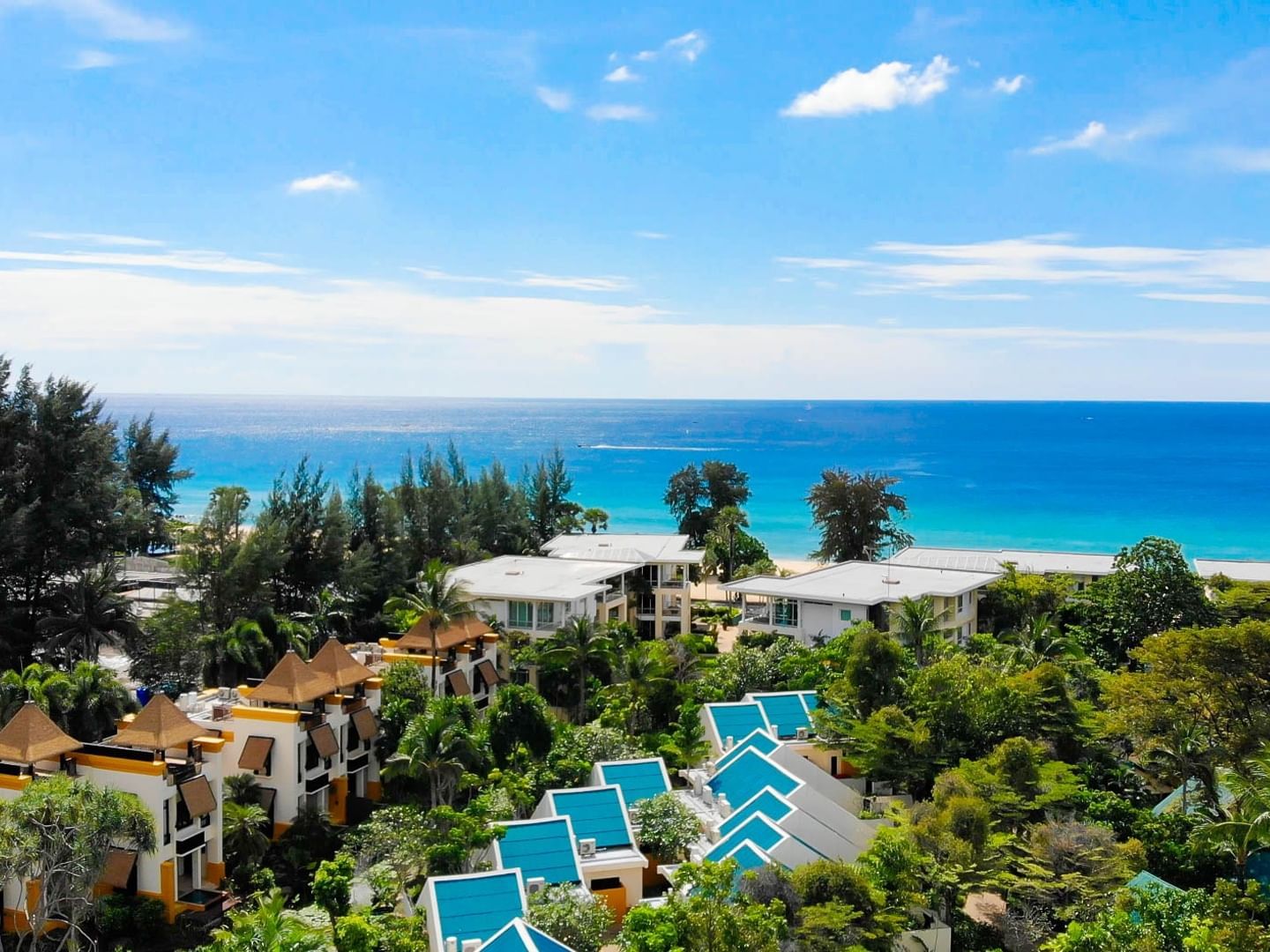 A stunning view of the crystal-clear turquoise waters of Karon Beach, surrounded by a lush tropical garden.