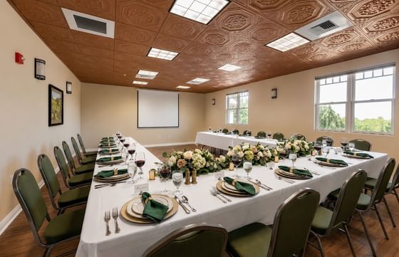 Long banquet table with white cloths and green chairs under a patterned ceiling at Oregon Garden Resort